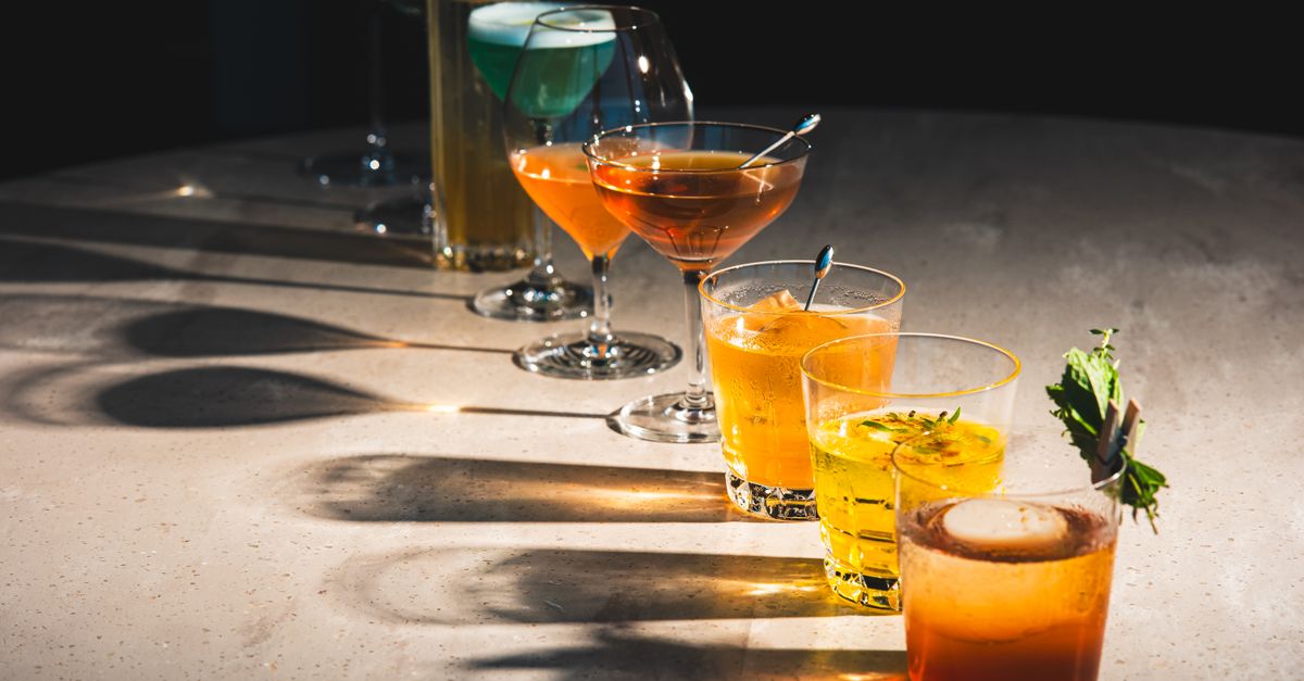 A colorful assortment of cocktails on a bar counter, showcasing diverse drink options.